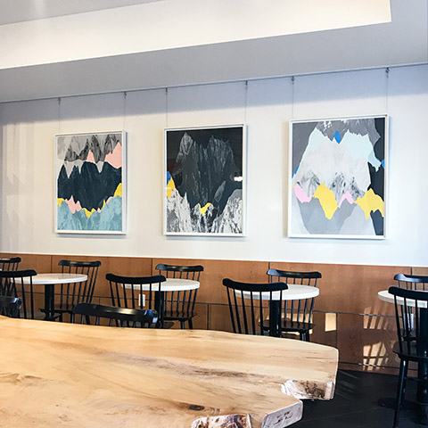 three artworks by jamie kripke hanging in a modern restaurant