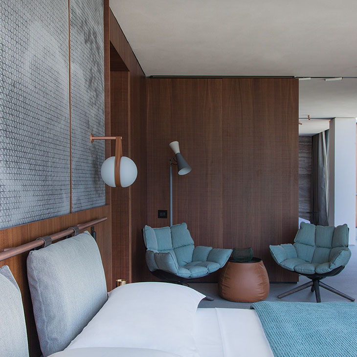 modern bedroom featuring two b&b italia husk armchairs with wood base