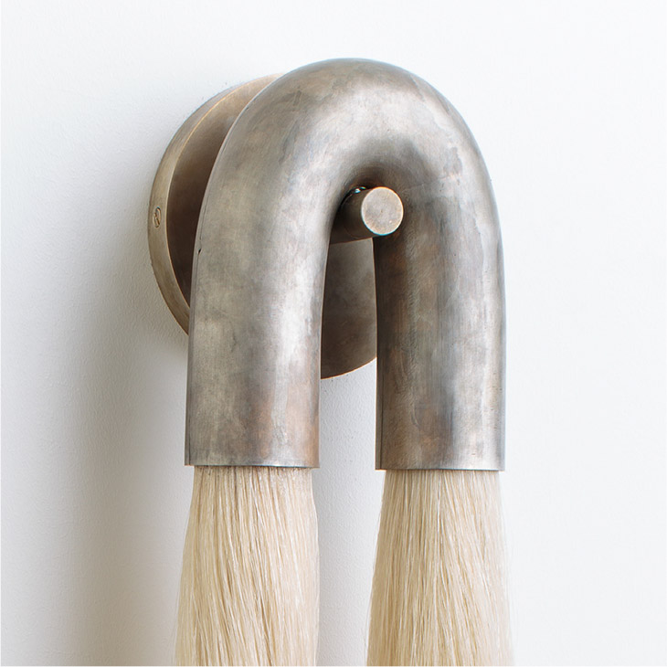 close up of an apparatus horsehair sconce with tarnished silver metal and flaxen hair