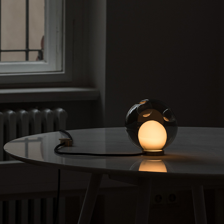 dark interior space featuring a glowing bocci 28t table lamp on a table